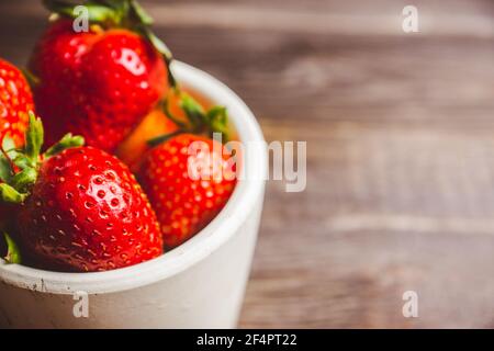 Frische reife Erdbeere auf dem dunklen rustikalen Hintergrund. Selektiver Fokus. Geringe Schärfentiefe. Stockfoto