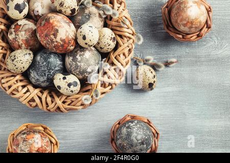 Ostern Zusammensetzung - mehrere Marmoreier mit natürlichen Farbstoffen in einem Korbnest und Körbe gemalt, Draufsicht. Stockfoto