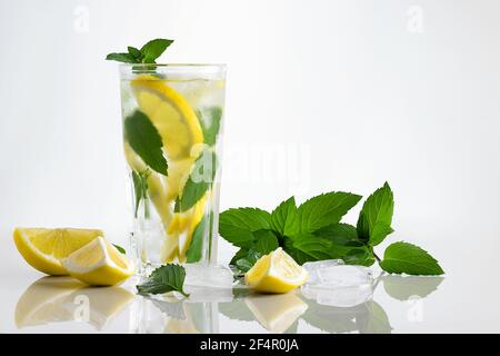 Frisch hausgemachter Cocktail in einem hohen Glas mit Zitrone, Minze und Eis auf weißem Hintergrund, Kopierraum. Stockfoto