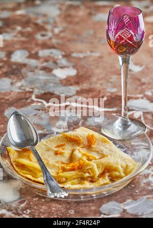 Pfannkuchen mit Crepe Suzette, in durchsichtiger Platte mit Glas Likör. Französische Küche, Schritt für Schritt Rezept Stockfoto