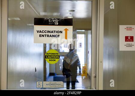 Bild zeigt das Innere einer Gesundheitseinrichtung mit Glas Automatische Tür mit einem Schild auf der Aufschrift Eingang von Die Impfstelle COVID-19 Stockfoto
