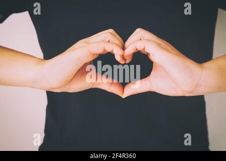 Frau tragen schwarzes Hemd und Geste Hände für Herzform. Konzept für Liebe, Hilfe, Freundlichkeit, spenden, Herzgesundheit, Psychische Gesundheit, medizinisch, positiv Stockfoto