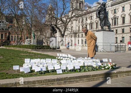 WESTMINSTER LONDON, GROSSBRITANNIEN 22. MÄRZ 2021. Eine Frau betrachtet die Blumen und Botschaften, die auf dem Parlamentsplatz in Erinnerung an die Opfer des Terroranschlags an die Westminster Bridge von 2017 platziert wurden. Heute markiert vier Jahre seit dem Angriff l. Heute ist der 4th. Jahrestag des Todes von PC Keith Palmer, der während eines Angriffs auf die Westminster Bridge von Khalid Masood im New Palace Yard getötet wurde. PC Keith Palmer wurde posthum mit der George Medal ausgezeichnet, der zweithöchsten Auszeichnung für Gallanterie Credit amer ghazzal/Alamy Live News Stockfoto