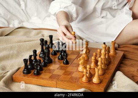 Schachspielerin Frau Lernt Schacheröffnung, Indem Sie Mit Sich Selbst Spielt. Weißer Bauer Einen Schritt Vorwärts. Schachbrett Aus Holz Mit Schachfiguren Auf Hellem Hintergrund. Strategie Board Spiel Gespielt. Nahaufnahme Toned Photo Stockfoto