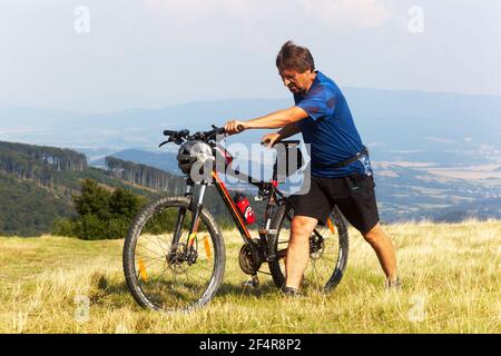 Mann, der mit dem Fahrrad läuft, Mann, der ein Mountainbike hinaufschiebt Stockfoto