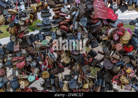 Tomsk, Russland - 10. September 2019: Liebesschlösser auf einem Zaun auf einem Brdigd in Tomsk, viele Vorhängeschlösser in verschiedenen Farben und Größen, Russland, Sibirien. Stockfoto