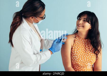 Schöne Frau in der Arztpraxis bekommen Impfstoff. Medizinische Fachkraft, die Injektion auf Arm der jungen Frau. Stockfoto