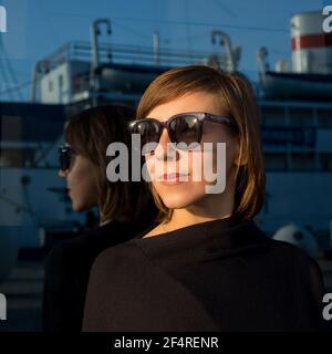 Porträt einer Frau mit kurzen Haaren in Sonnenbrille auf Blau Hintergrund Stockfoto