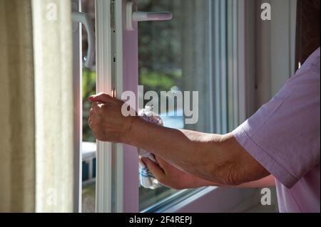 Mittelteil der Frau, die ein Fenster mit Tuch putzt Stockfoto