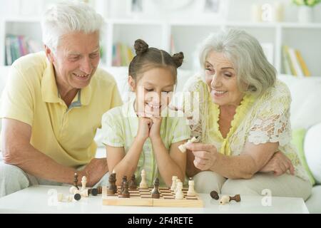 Ältere Frau, Mann spielt Schach mit Enkelin Stockfoto