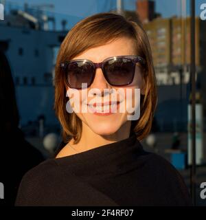 Porträt einer Frau mit kurzen Haaren in Sonnenbrille auf Blau Hintergrund Stockfoto