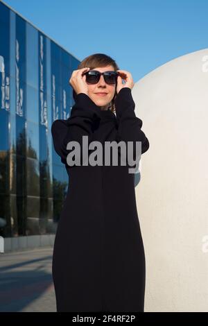 Porträt einer Frau mit kurzen Haaren in Sonnenbrille auf Blau Hintergrund Stockfoto