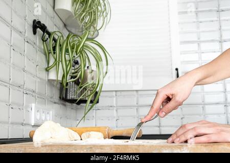 Frau piercing den Teig mit einer Gabel für blindes Backen. Frauenhände machen Plätzchen Gebäck für Torte. Teigherstellung durch weibliche Hände in weißer moden kitche Stockfoto