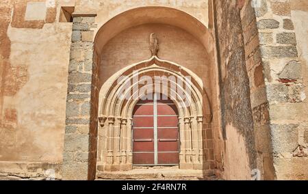 Veranda einer alten katholischen Kapelle in Spanien, mit Holztür und Fassade aus geschnitztem Stein und adobe Stockfoto