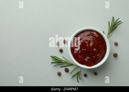 Schüssel mit Barbecue-Sauce und Gewürzen auf hellgrauem Hintergrund Stockfoto
