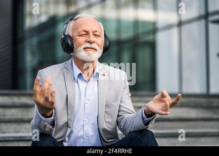 Ein glücklicher Geschäftsmann meditiert nach der Arbeit vor dem Firmengebäude. Stockfoto