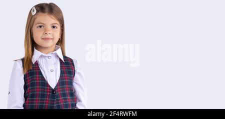 Banner – Langformat, grauer Hintergrund. Happy cute Kind Mädchen in der Schule Uniform Blick auf die Kamera. Schulmädchen mit freundlichen Gesichtsausdruck. Konzept von Stockfoto