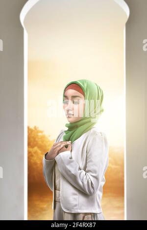 Asiatische muslimische Frau in einem Schleier stehend, während die Hände angehoben Und auf der Moschee beten Stockfoto