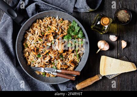 Klassisches cremiges Pilzrisotto mit geriebenem Parmesankäse in einer Pfanne, flaches Lay, italienische Küche Stockfoto