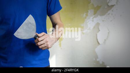 Bauarbeiter stehend mit Kitt Messer in der Hand auf alten Wand Hintergrund. Banner Kopie Raum Stockfoto