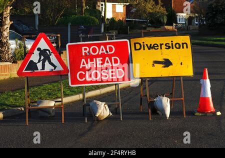 Temporäre Straßenschilder, die Straßenarbeiten anzeigen, Straße vor geschlossen, und Umleitung in einem Wohngebiet von Hellesdon, Norfolk, England, Vereinigtes Königreich. Stockfoto