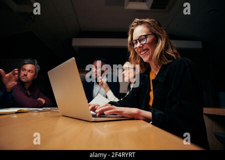 Porträt einer jungen erfolgreichen Geschäftsfrau, die mit einem Kollegen am Laptop sitzt Am Arbeitsplatz Stockfoto