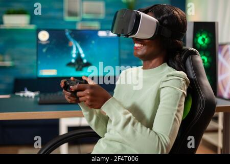 Schwarze Frau mit Spaß spielen Videospiele mit vr Headset mit Controller. Virtuelle Weltraum-Shooter-Videospiel-Meisterschaft im Cyberspace, eSport Spieler auf dem pc während Gaming-Turnier. Stockfoto