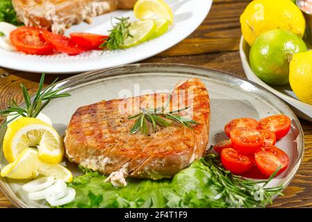 Thunfischsteak auf dem elektrischen Grill gekocht. Thunfisch serviert auf einem Teller mit frischen Kräutern und Gemüse. Gesunde nahrhafte, gesunde Ernährung für eine gesunde Stockfoto