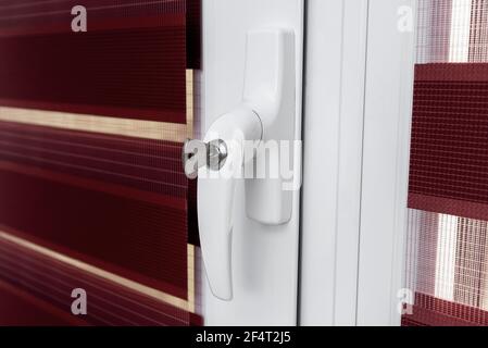 Sicheres PVC-Fenster mit abschließbarem Griff.das Konzept, ein Kind vor dem Herausfallen aus den Fenstern zu schützen. Weißes Kunststofffenster mit Fensterläden. Tasten im Fenster. Selektiver Fokus Stockfoto