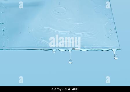 Abstrakter Hintergrund. Wassertropfen auf dem Fenster. Wasser gießt auf ein Stück klares Glas Stockfoto