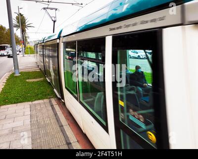 Mann mit Maske sitzt in einer Straßenbahn. Blick von draußen. Barcelona, Katalonien, Spanien Stockfoto
