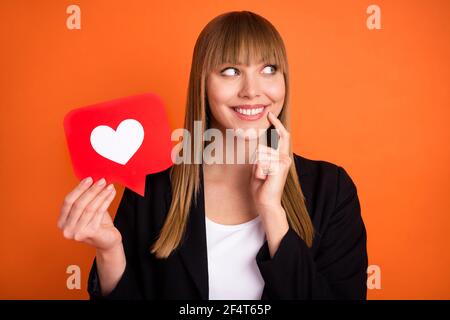 Portrait der schönen trendigen verträumt fröhlich Mädchen mit Papier rot Karte Web wie Denken isoliert über helle orange Farbe Hintergrund Stockfoto