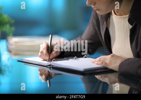 Nahaufnahme einer Frau Hände, die Notizen in einem Ring Ordner Notizbuch auf einem Schreibtisch in der Nacht um Zu Hause Stockfoto