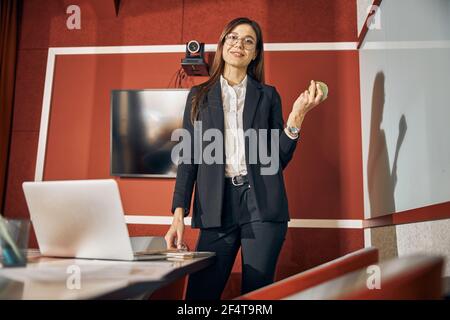 Lächelnder Büroangestellter in einem Anzug, der am Schreibtisch steht Stockfoto