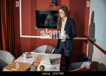 Junge Frau konzentrierte sich auf eine technische Zeichnung in der Hand Stockfoto