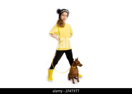 Kleines Mädchen mit Hund, schwarze und gelbe Kleidung. Weißer Hintergrund. Studioaufnahmen. Baby Haustiere Konzept. Frohe Kindheit Stockfoto