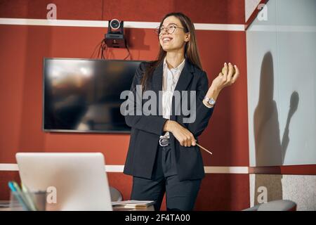 Fröhlicher Büroangestellter in Brillen und einem Anzug, der wegschaut Stockfoto
