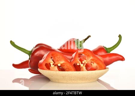 Zwei ganze und eine geschnittene reife Bio-Paprika lecker süßen Capia Paprika, auf einem hellen Keramik-Untertasse, auf einem weißen Hintergrund. Stockfoto