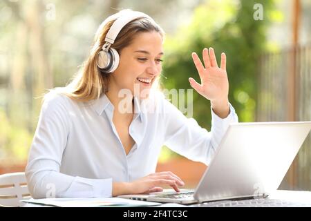 Glücklicher Unternehmer trägt Kopfhörer arbeiten Videoaufnahmen auf Laptop in einem Terrasse Stockfoto