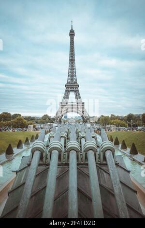Eiffelturm mit Kanonen, die an einem bewölkten Tag in Paris, Frankreich, darauf zeigen. Stockfoto