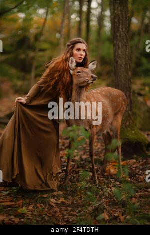 Rotschopf Mädchen mit Hirsch in einem langen Kleid Stockfoto