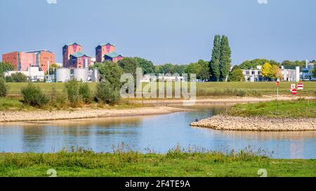 Niederländische Landschaft mit dem Fluss IJssel und seinen Auen in der Nähe der Stadt Deventer Hanze. Wohngebäude und Industriegebäude sind zu sehen. Stockfoto