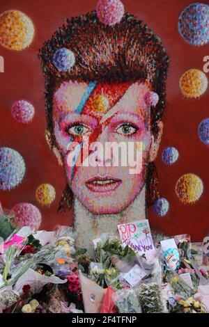 LONDON, UK - JANUAR 12 2016: Blumen, die David Bowie Fans nach seinem Tod auf dem Wandgemälde des Musikers in Brixton gelegt haben Stockfoto