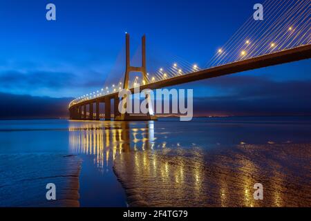 Nachtlichter auf der Lissabon-Brücke. Die Vasco da Gama Brücke ist ein Wahrzeichen und eine der längsten Brücken der Welt. Stadtlandschaft. Portugal ist ein Stockfoto