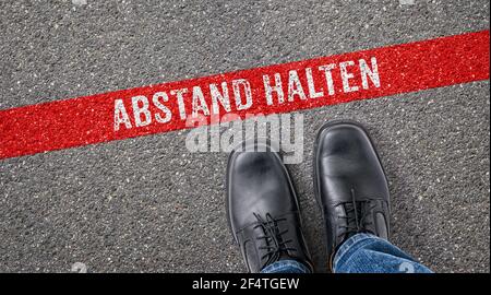 Rote Linie auf Asphalt - Abstand auf deutsch halten - Halten Sie sich zurück Stockfoto