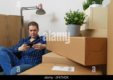 Mann mit Smartphone in neuer Wohnung. Stockfoto