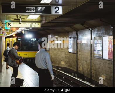 Tokio, Japan - U-Bahn kommt der Bahnhof und der Sicherheitsbeamte auf dem Bahnsteig. Stockfoto
