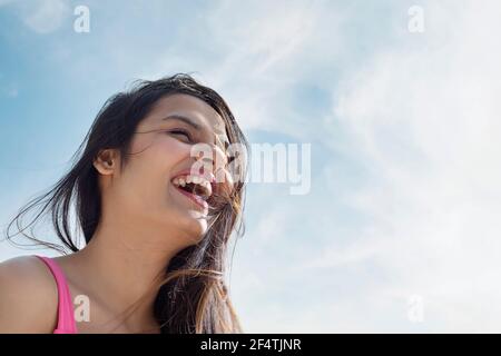 EINE JUNGE FRAU, DIE LACHT UND EINEN SONNIGEN TAG GENIESST Stockfoto