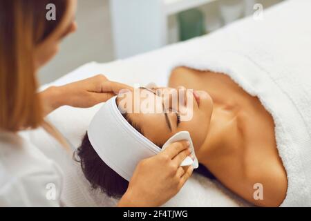 Weibliche Kosmetikerin wischt das Gesicht eines jungen Mädchens mit Servietten, die sie für kosmetische Eingriffe vorbereiten. Stockfoto