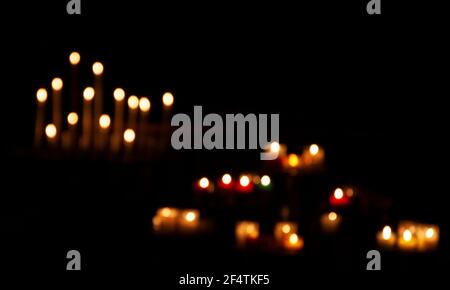 Verschwommenes Foto von Kerzen im dunklen Tempel. Bokeh. Hintergrund des Memorial Light. Gebet für kranke Geliebte. Gebet für kranke Personen Konzept. Stockfoto